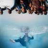 Photo by Thero Makepe of a person in a suit submerged in water with a group of people overlaid upside-down at the top of the image