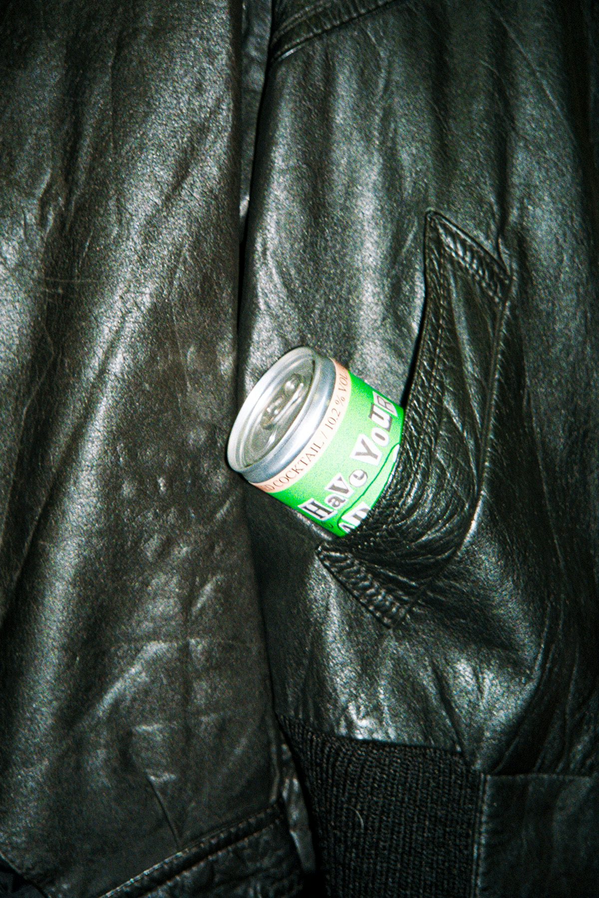 A green can of drink sticking out of a pocket in a leather jacket