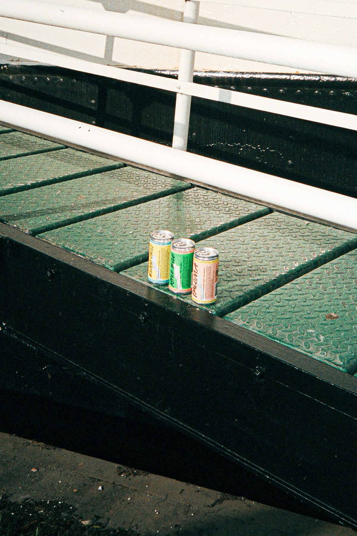 Three drinks cans lined up on a metal outdoor ramp