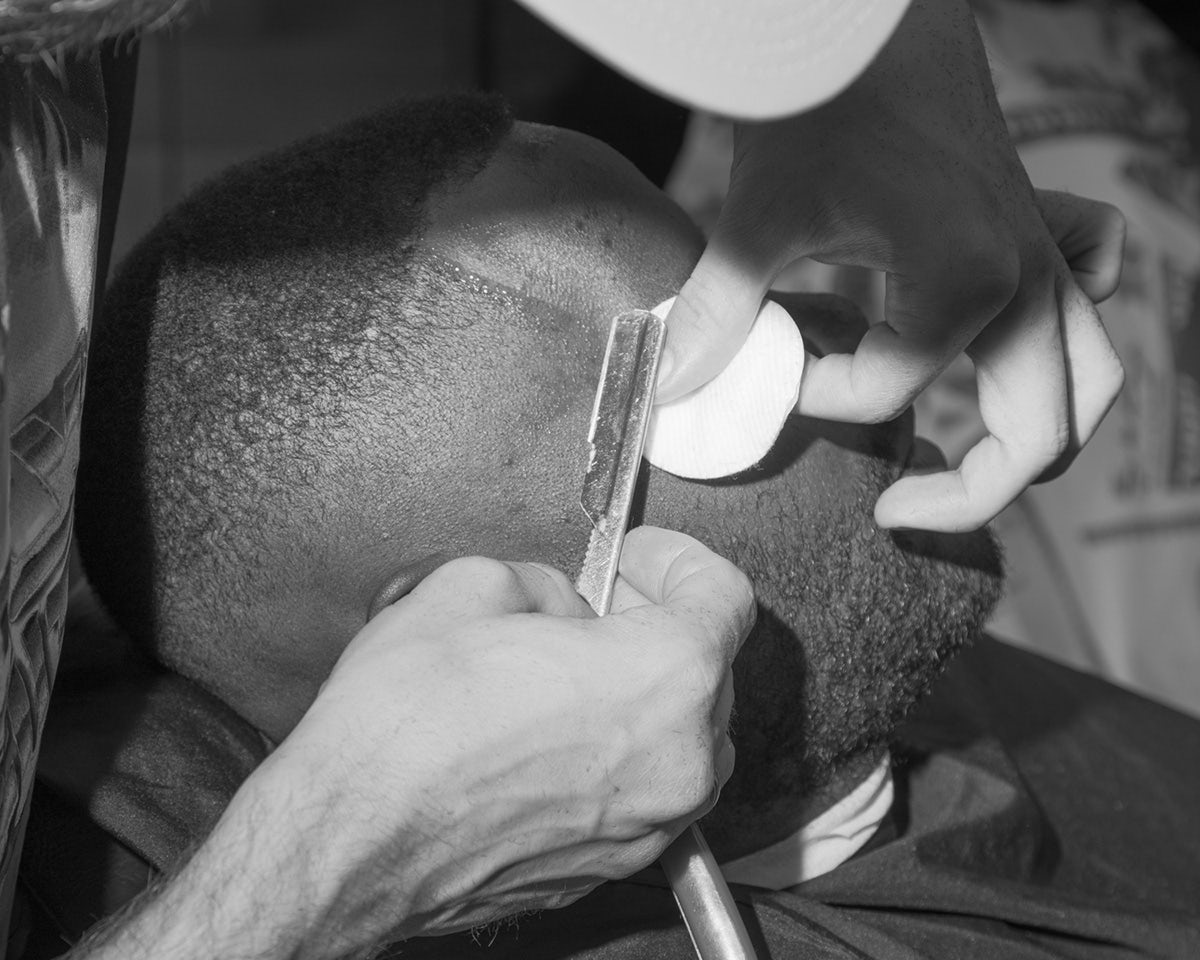 Black and white photo by Karol Szymkowiak showing a person having their head shaved