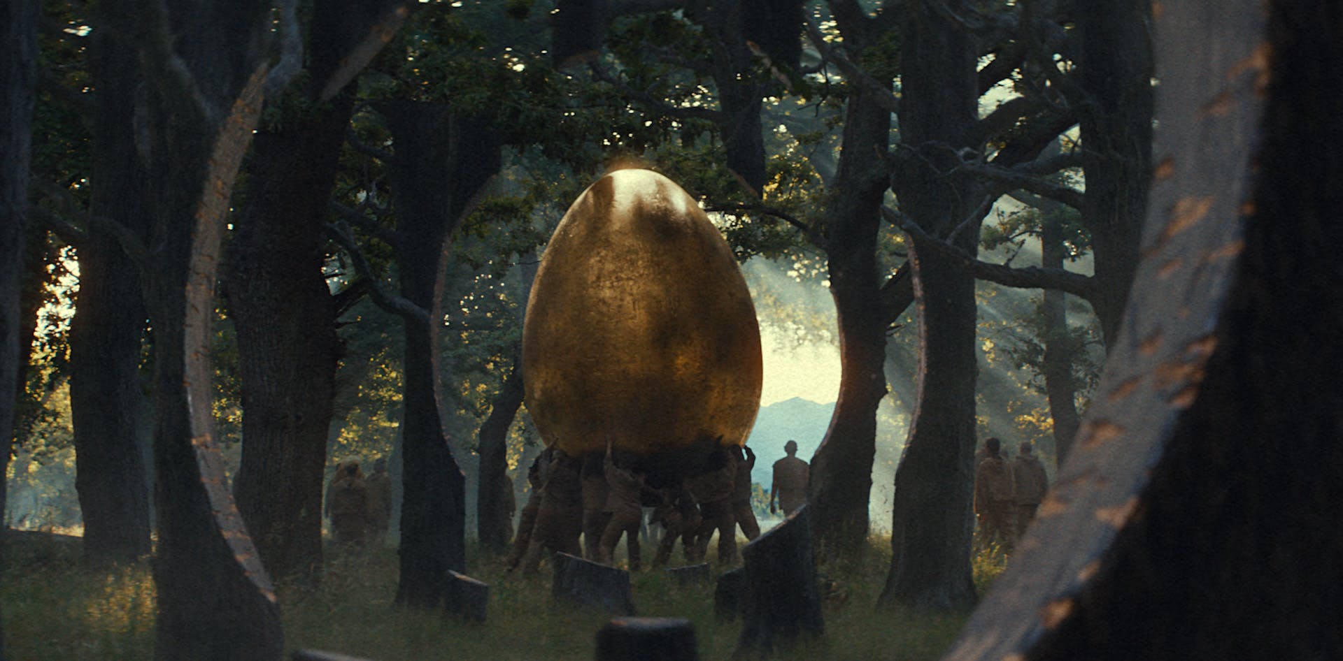 Still from KFC's All Hail Gravy advert showing a group of people wearing brown outfits carrying a large golden egg over their heads through a forest
