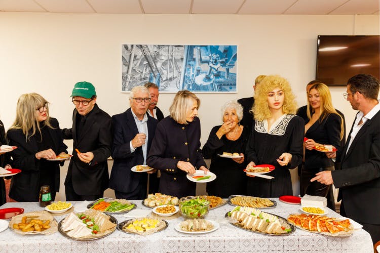 Photo from Julie Bullard by Nadia Lee Cohen and Martin Parr showing a gathering of people all dressed in black at a buffet table