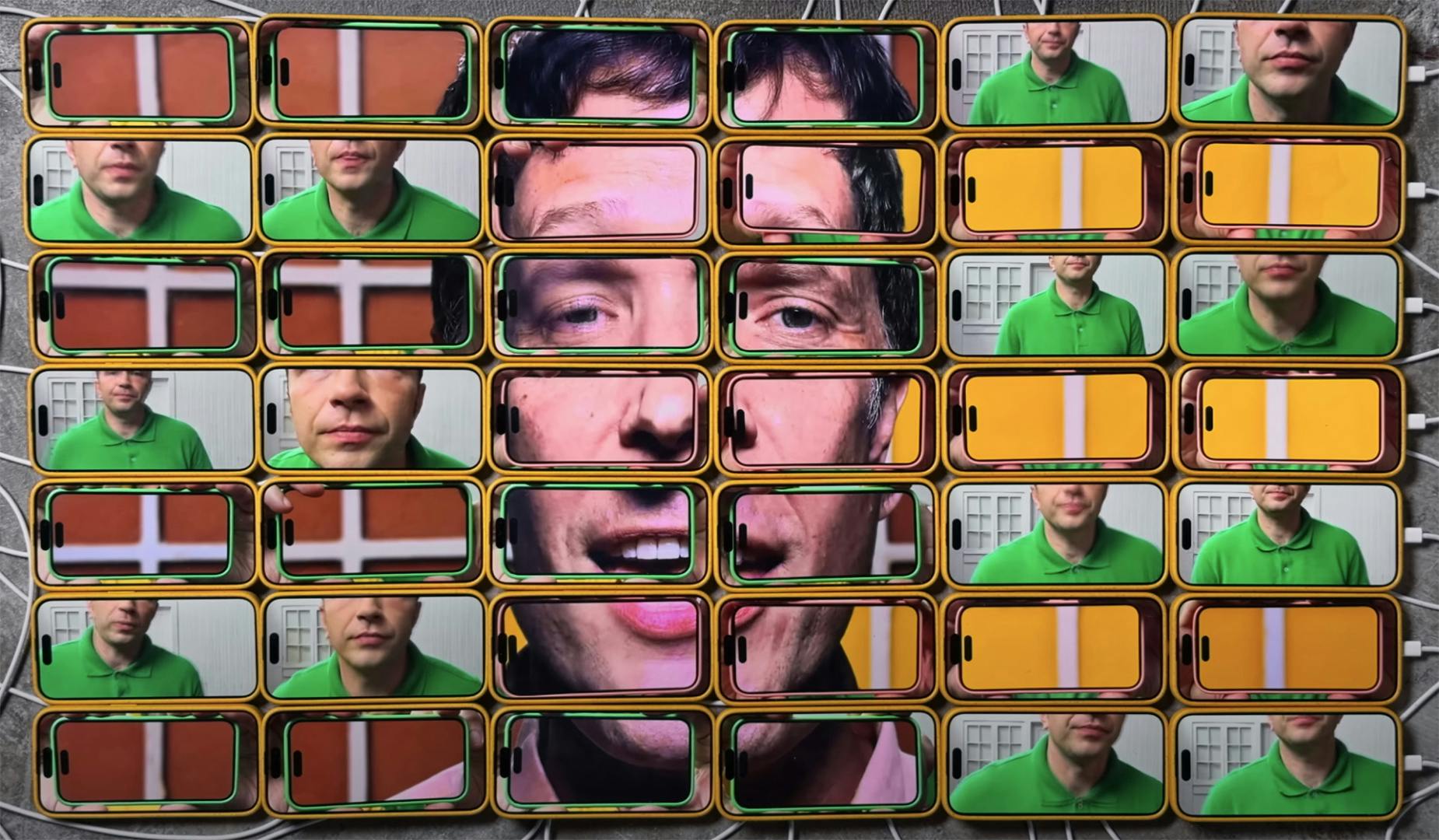 Still from an OK Go music video showing an image of a person's face spread over a grid of phone screens