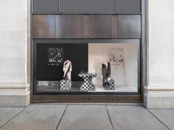 Selfridges store window featuring an installation with a chess table and chessboard inspired seating and clothing on mannequins