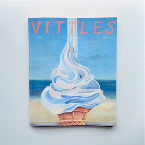 Cover of Vittles magazine issue one featuring an illustration of an soft serve ice cream pouring from above with a beachfront in the background